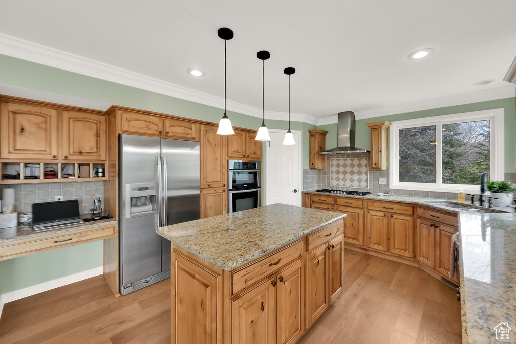 Kitchen with a sink, light wood-style floors, stainless steel appliances, and wall chimney exhaust hood