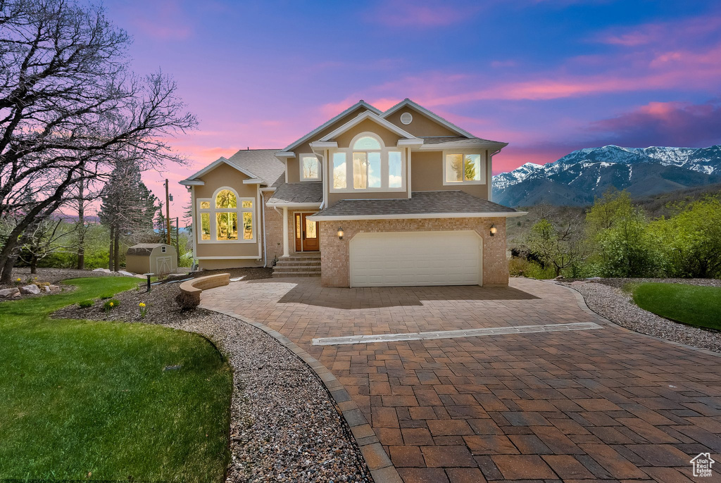 View of front of home with decorative driveway, a garage, a mountain view, and stucco siding