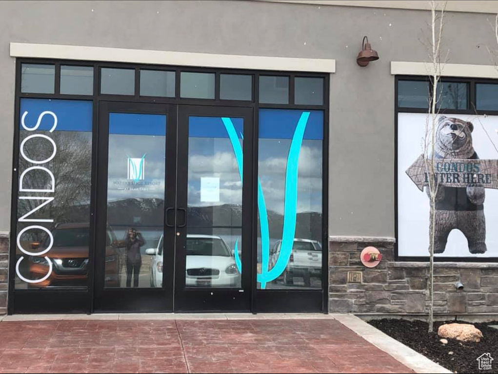 Entrance to property with stucco siding, french doors, and stone siding