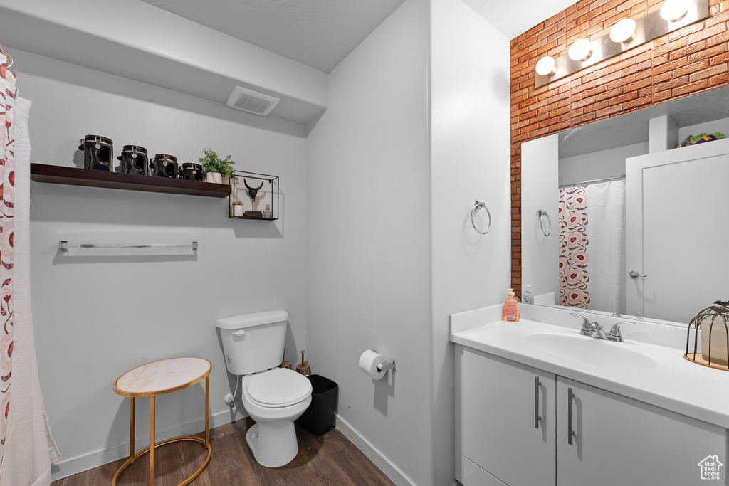 Full bath with visible vents, wood finished floors, vanity, baseboards, and toilet