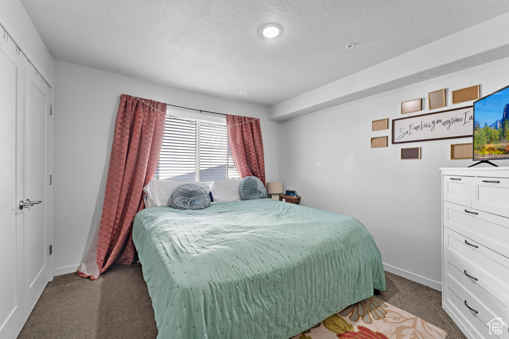 Carpeted bedroom featuring baseboards and a textured ceiling