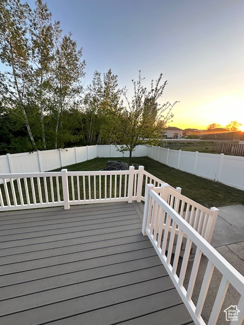 Deck at dusk with a lawn and a fenced backyard