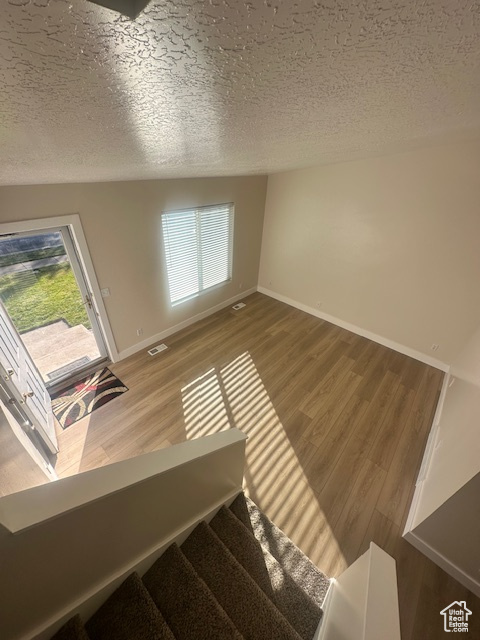 Interior space featuring visible vents, stairs, wood finished floors, baseboards, and a textured ceiling