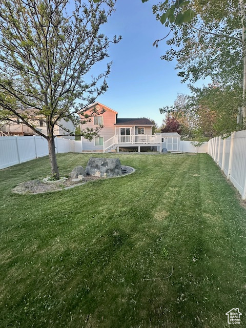 View of yard featuring a fenced backyard, an outbuilding, a deck, and a storage shed