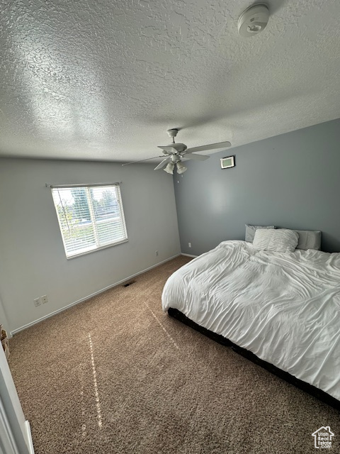 Carpeted bedroom featuring baseboards, ceiling fan, a textured ceiling, and visible vents