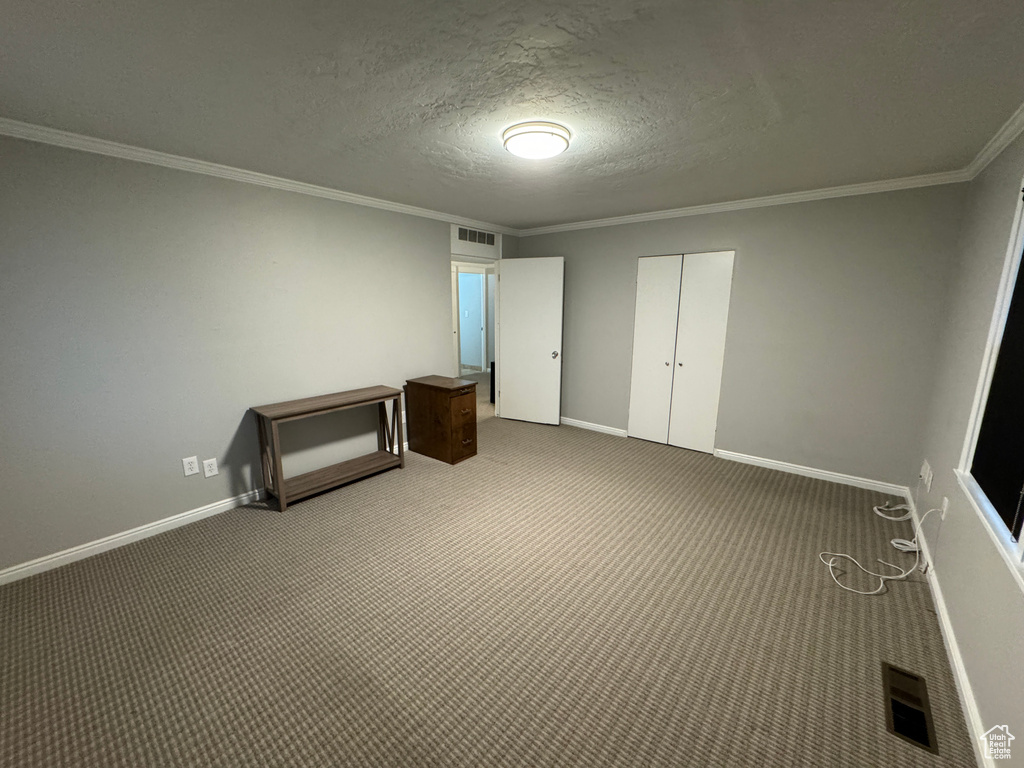 Unfurnished bedroom featuring visible vents, carpet flooring, baseboards, and crown molding