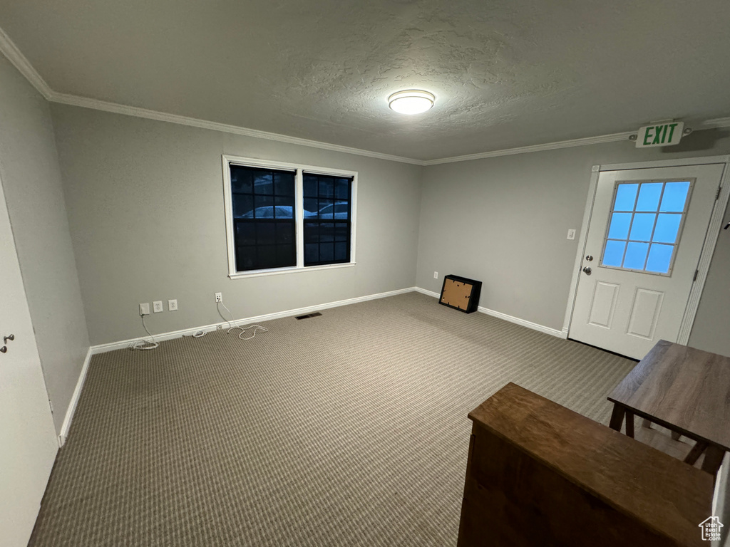 Interior space with a textured ceiling, baseboards, and ornamental molding