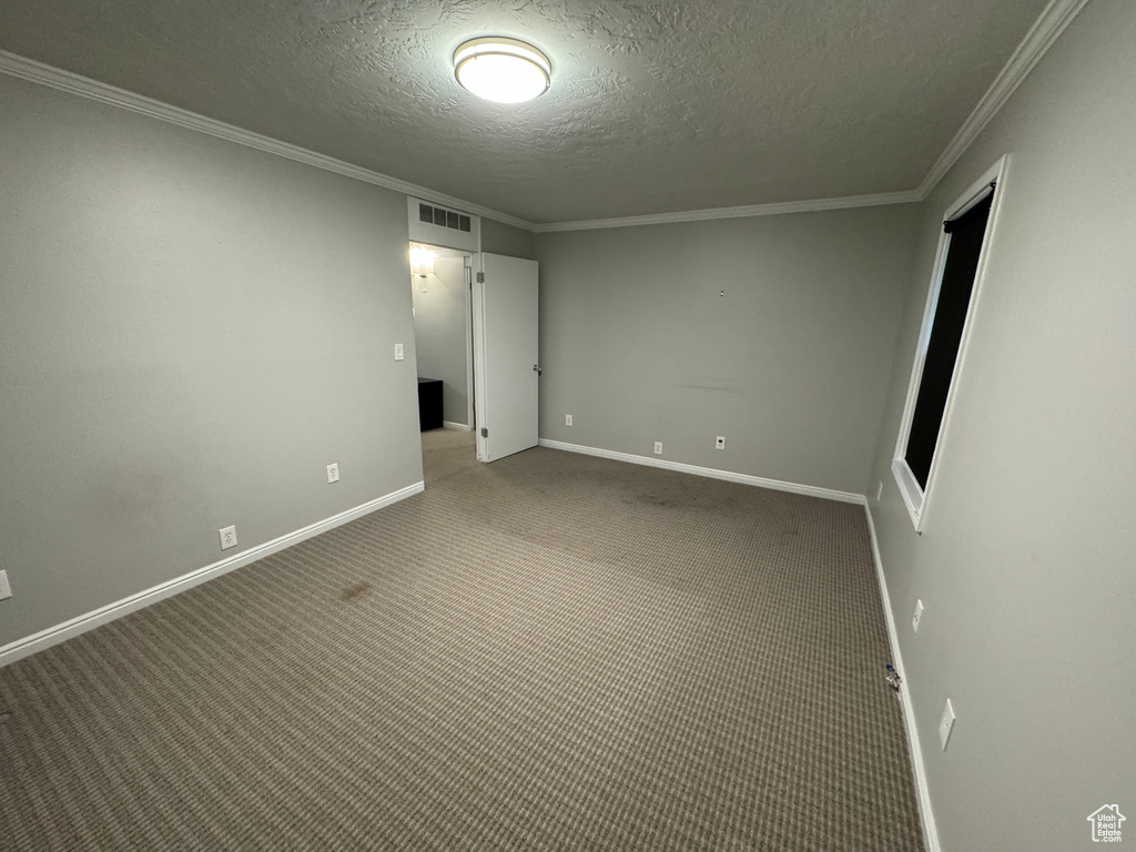 Unfurnished room with ornamental molding, carpet flooring, a textured ceiling, and visible vents