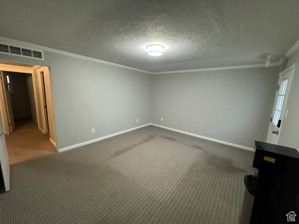 Empty room featuring crown molding, baseboards, carpet, and visible vents