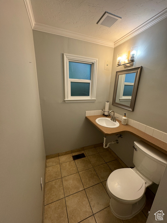 Half bathroom featuring toilet, tile patterned floors, visible vents, and a sink