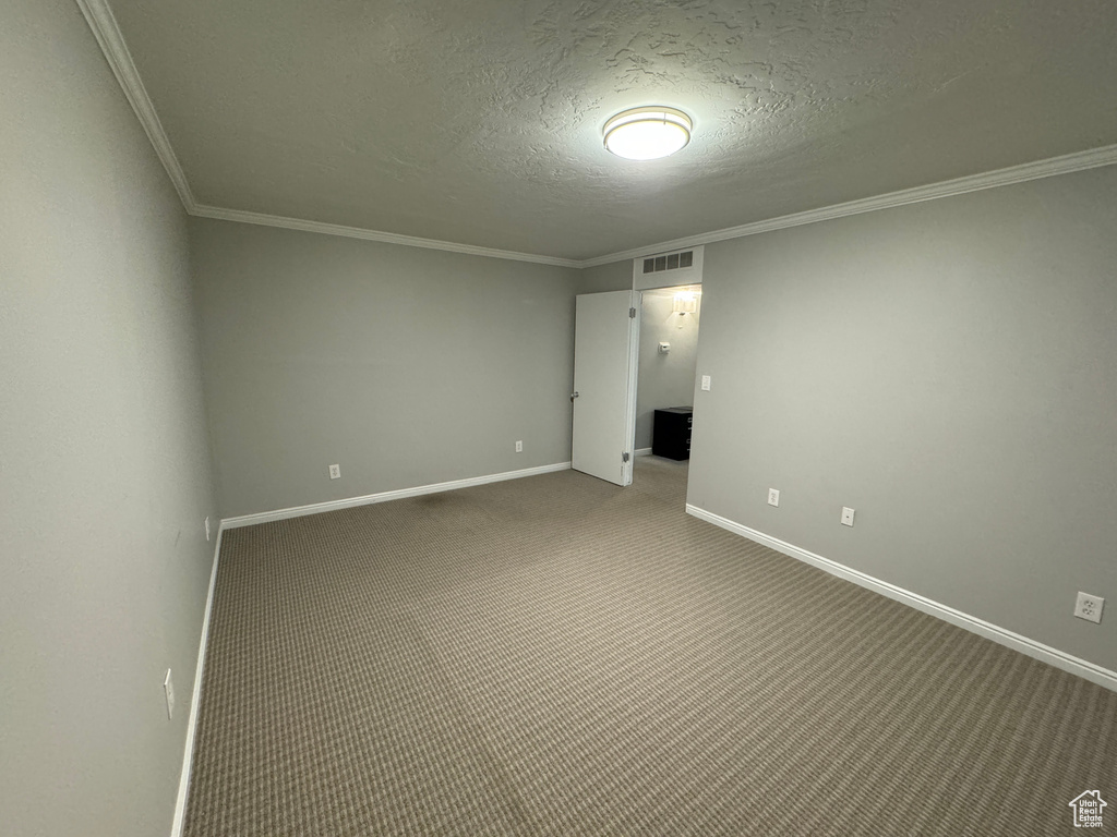 Unfurnished room featuring a textured ceiling, visible vents, crown molding, carpet floors, and baseboards