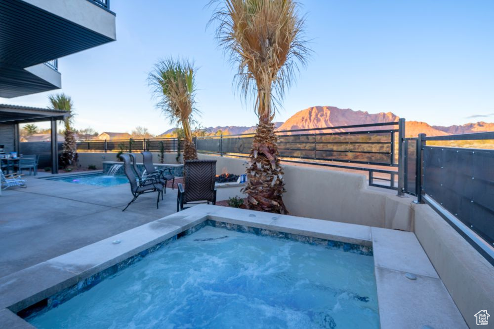 View of pool with a patio area, a fenced in pool, a mountain view, a fenced backyard, and a jacuzzi