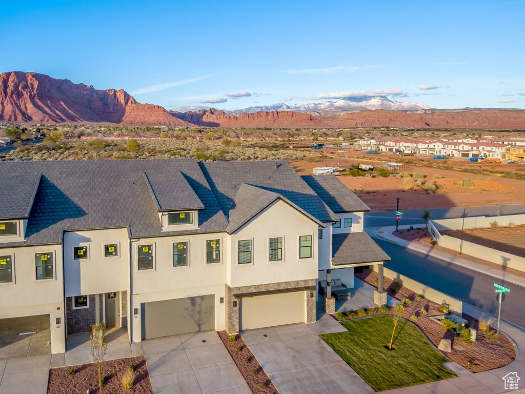 View of front of house with stucco siding, a garage, driveway, and a mountain view