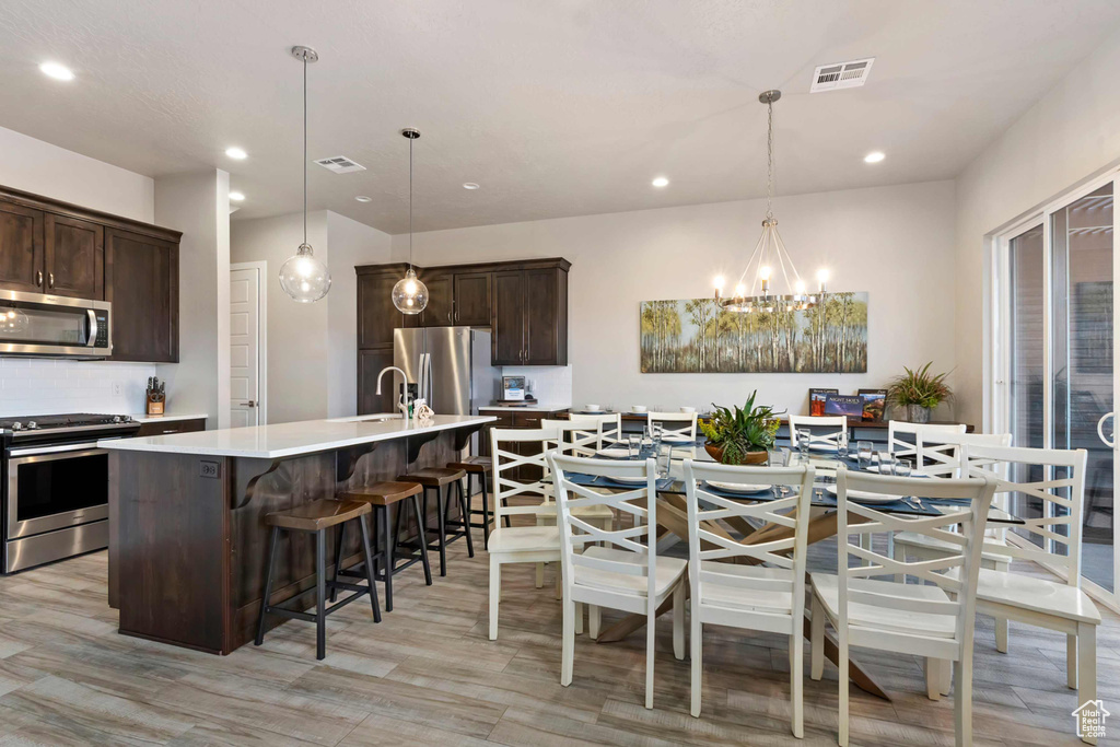 Kitchen featuring stainless steel appliances, dark brown cabinetry, a chandelier, recessed lighting, and light countertops