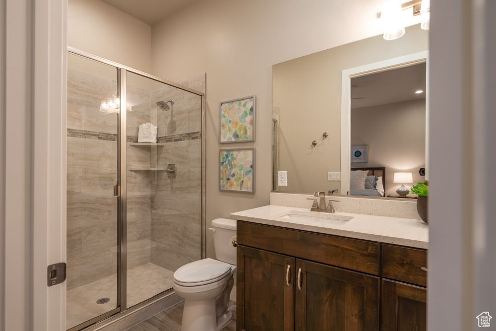 Ensuite bathroom featuring vanity, connected bathroom, toilet, and a shower stall