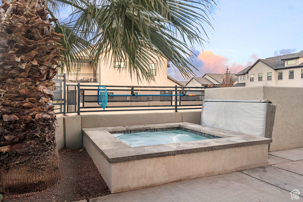 View of pool with an in-ground hot tub and fence