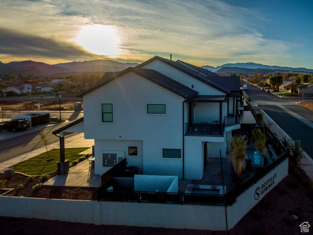 Back of property at dusk featuring a mountain view, a patio, fence, and stucco siding