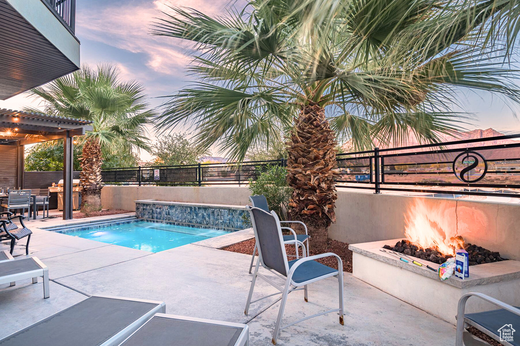 Pool at dusk with a patio, a fenced backyard, and an outdoor fire pit