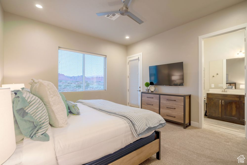 Bedroom with visible vents, light carpet, recessed lighting, a sink, and ensuite bath