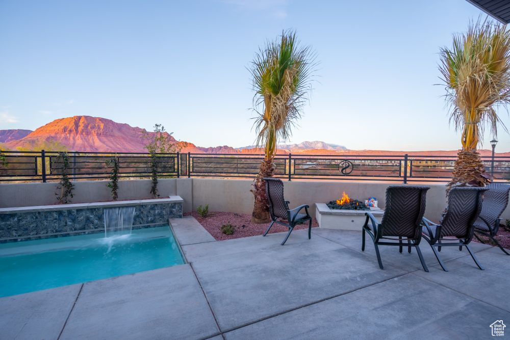 View of pool featuring a fenced in pool, a fenced backyard, an outdoor fire pit, and a mountain view