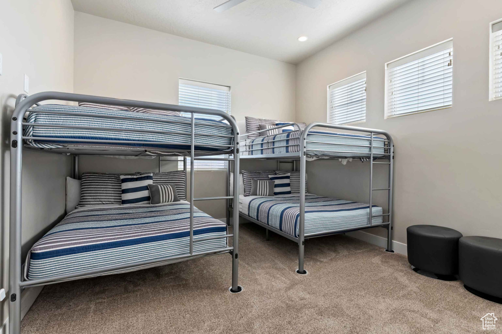 Carpeted bedroom with multiple windows, a ceiling fan, and baseboards