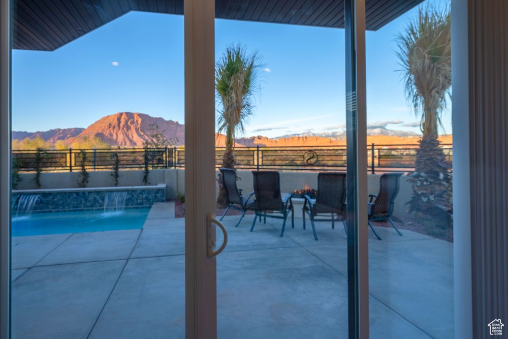 View of pool featuring a patio area, a fenced in pool, a mountain view, a fenced backyard, and a fire pit