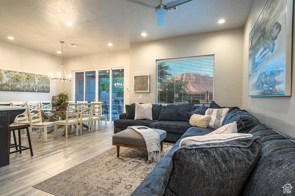 Living area with recessed lighting, light wood finished floors, a textured ceiling, and a chandelier