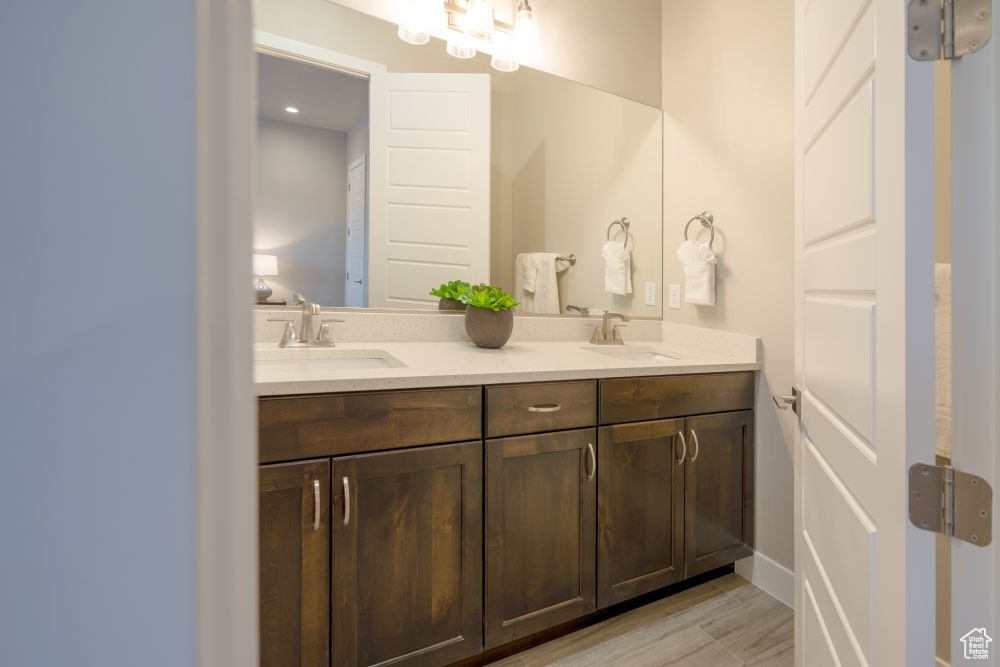 Bathroom with a sink, double vanity, and wood finished floors