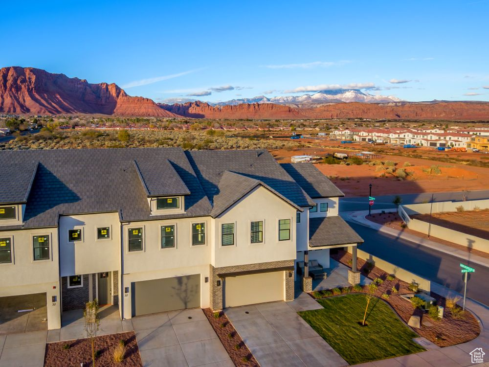 View of front facade featuring a garage, driveway, a mountain view, and stucco siding