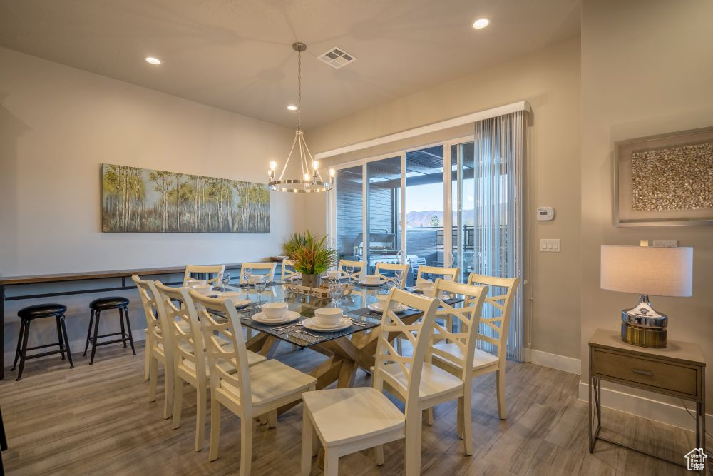 Dining area featuring visible vents, wood finished floors, baseboards, recessed lighting, and a notable chandelier