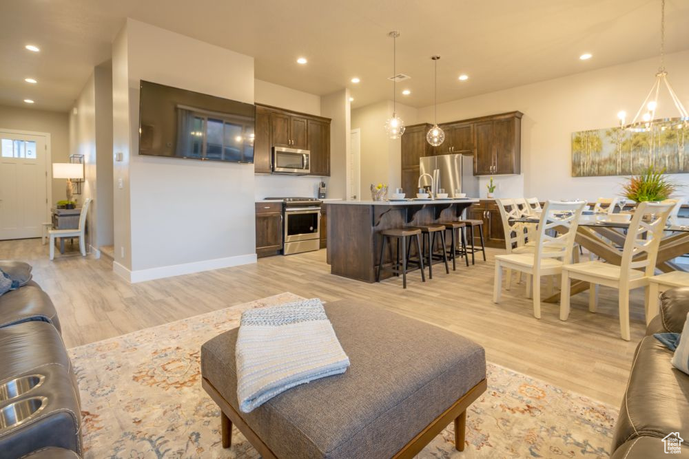 Living area featuring baseboards, recessed lighting, light wood-style flooring, and a notable chandelier
