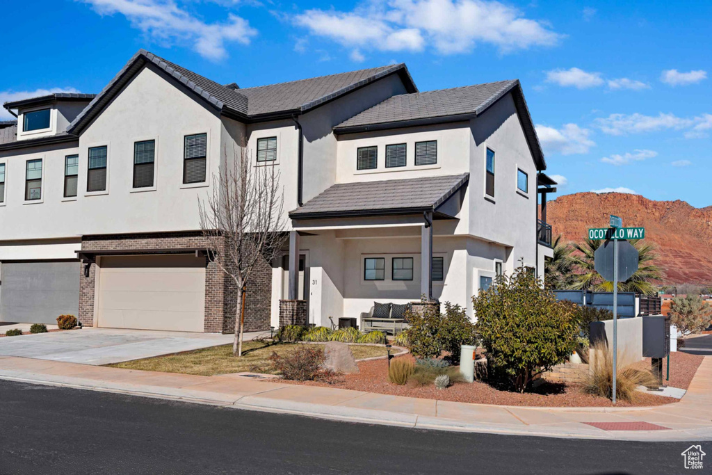 View of front of property with a garage, driveway, and stucco siding