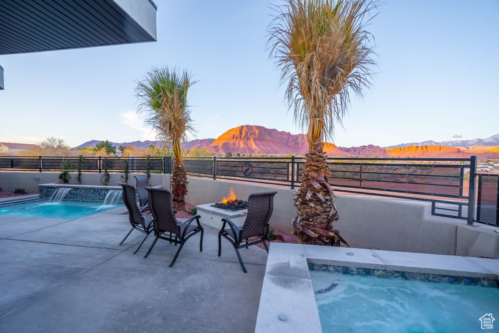 View of swimming pool featuring a fenced in pool, a fenced backyard, a fire pit, and a mountain view