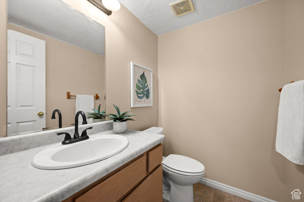 Half bathroom featuring vanity, baseboards, toilet, and visible vents