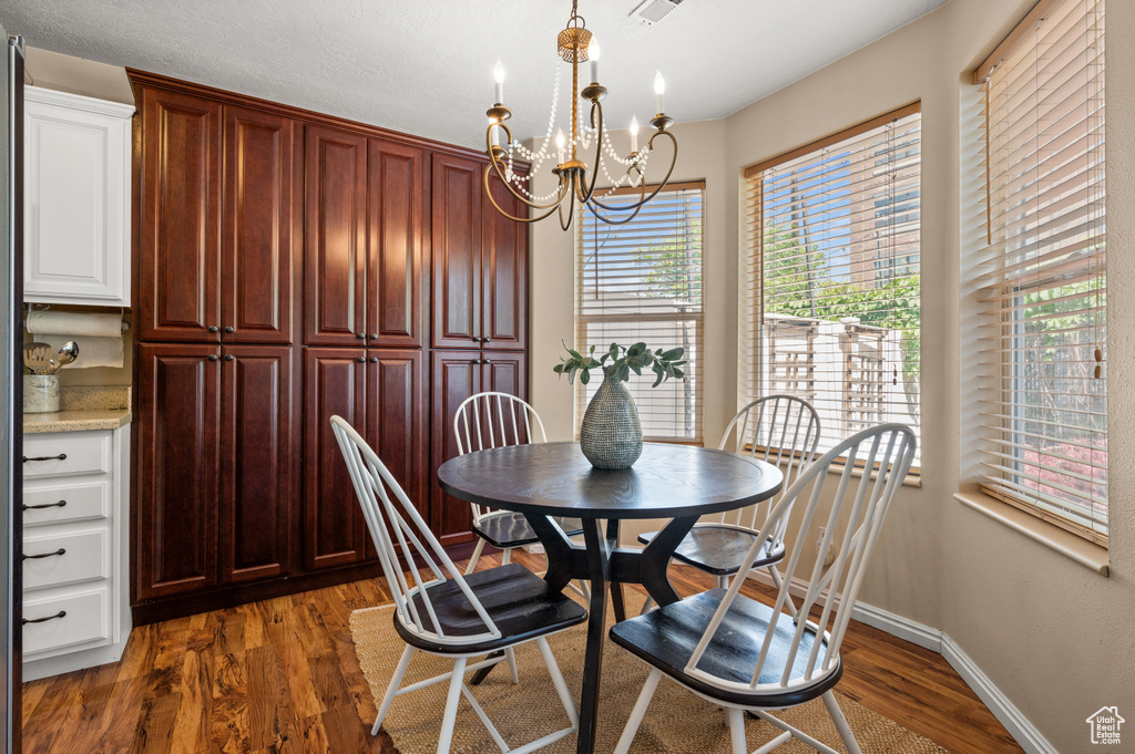 Dining area featuring baseboards, dark wood finished floors, and a chandelier