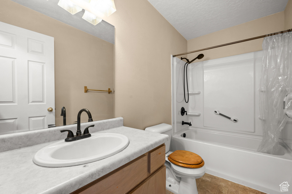 Full bathroom featuring toilet, a textured ceiling, shower / tub combo with curtain, and vanity