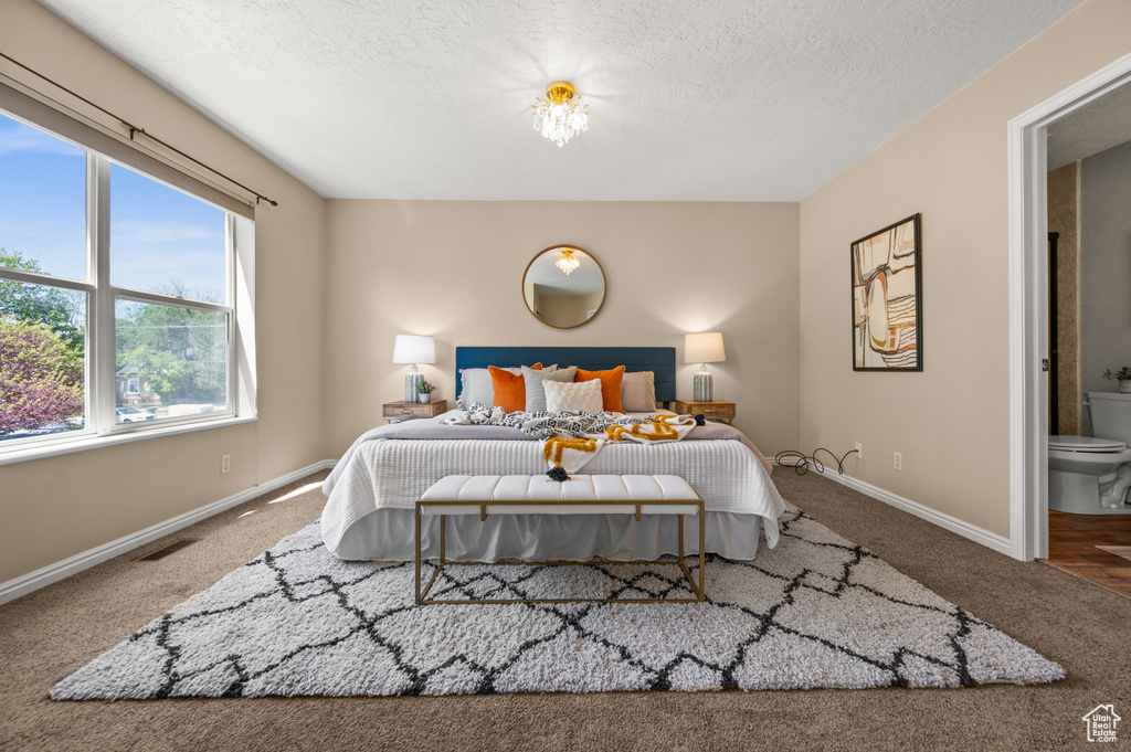 Bedroom featuring baseboards, carpet, a textured ceiling, and visible vents