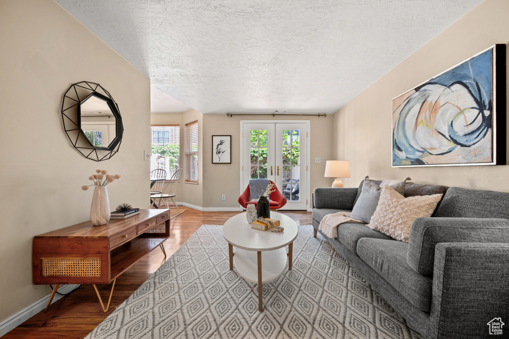 Living area featuring a textured ceiling, baseboards, french doors, and wood finished floors