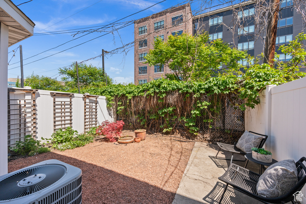 View of patio with central air condition unit and fence