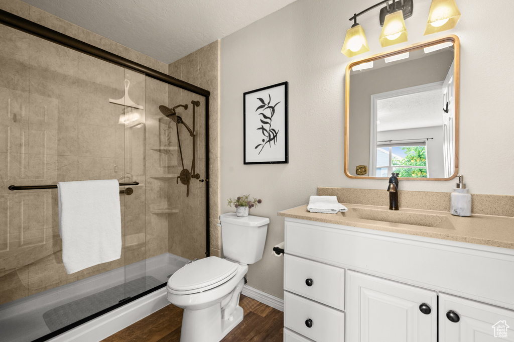 Bathroom with a shower stall, wood finished floors, vanity, baseboards, and toilet
