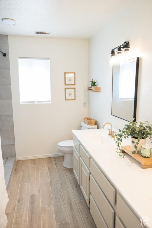 Bathroom with visible vents, wood finished floors, a wealth of natural light, and tiled shower
