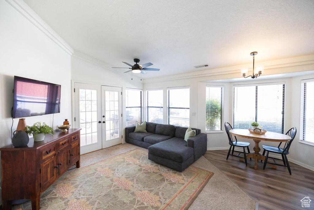 Living room with visible vents, ornamental molding, lofted ceiling, wood finished floors, and french doors