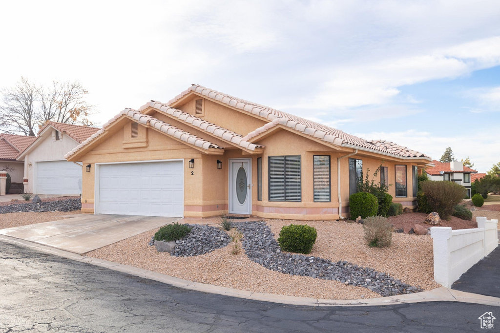 View of front of home with fence, an attached garage, stucco siding, a tiled roof, and driveway