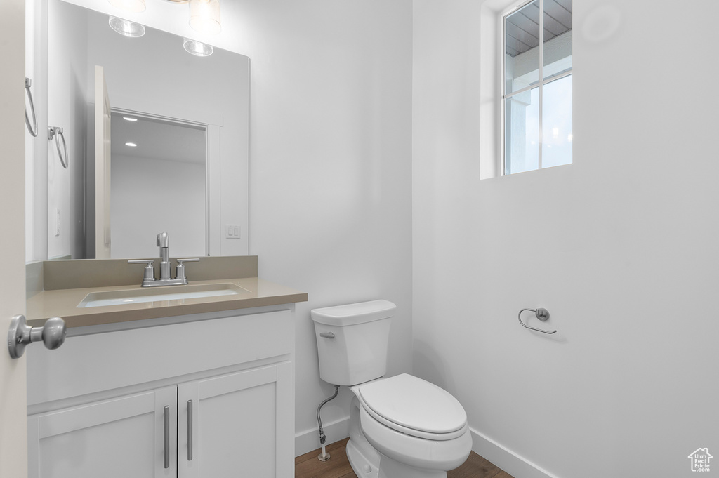 Bathroom with baseboards, vanity, toilet, and wood finished floors