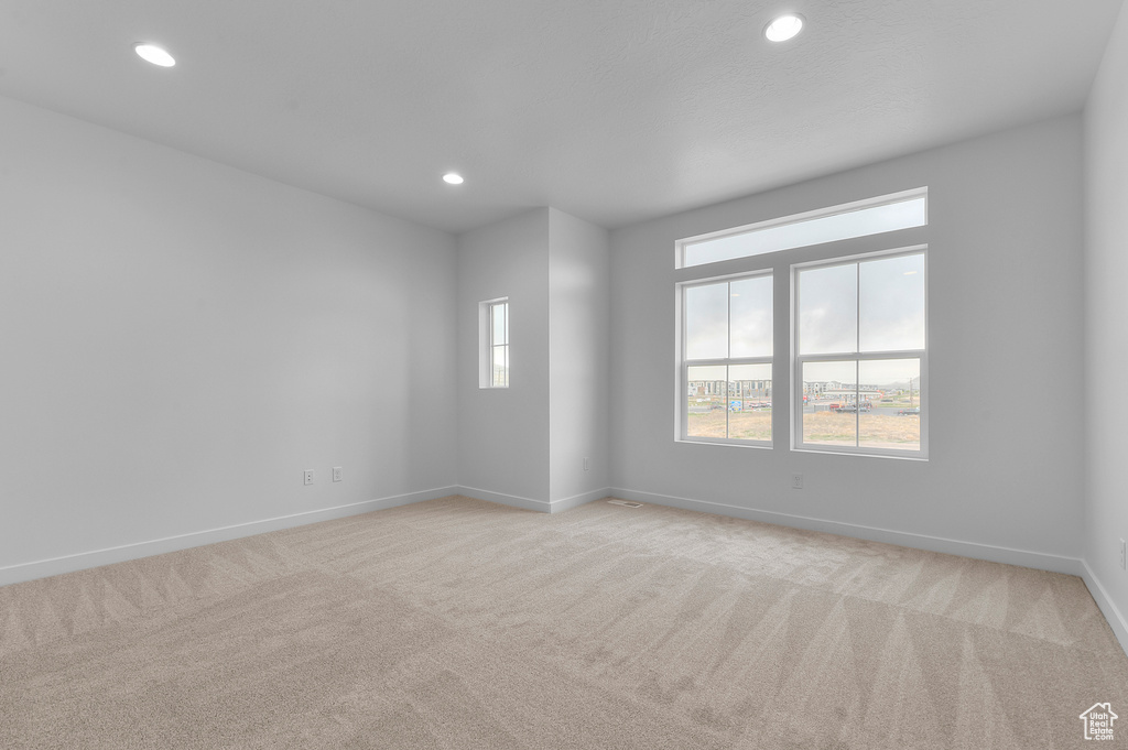 Spare room with baseboards, recessed lighting, and light colored carpet
