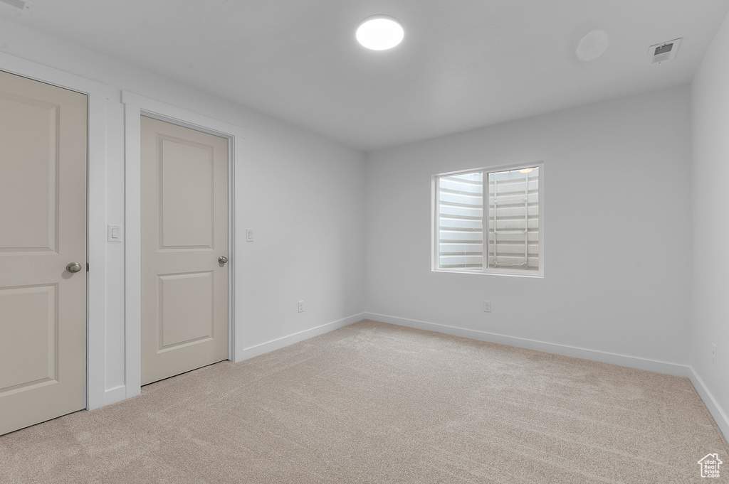 Unfurnished bedroom with baseboards, visible vents, and light carpet