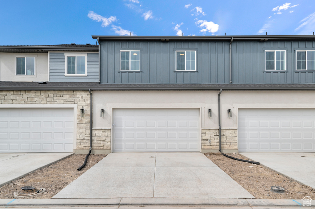 View of property featuring board and batten siding, an attached garage, and stone siding