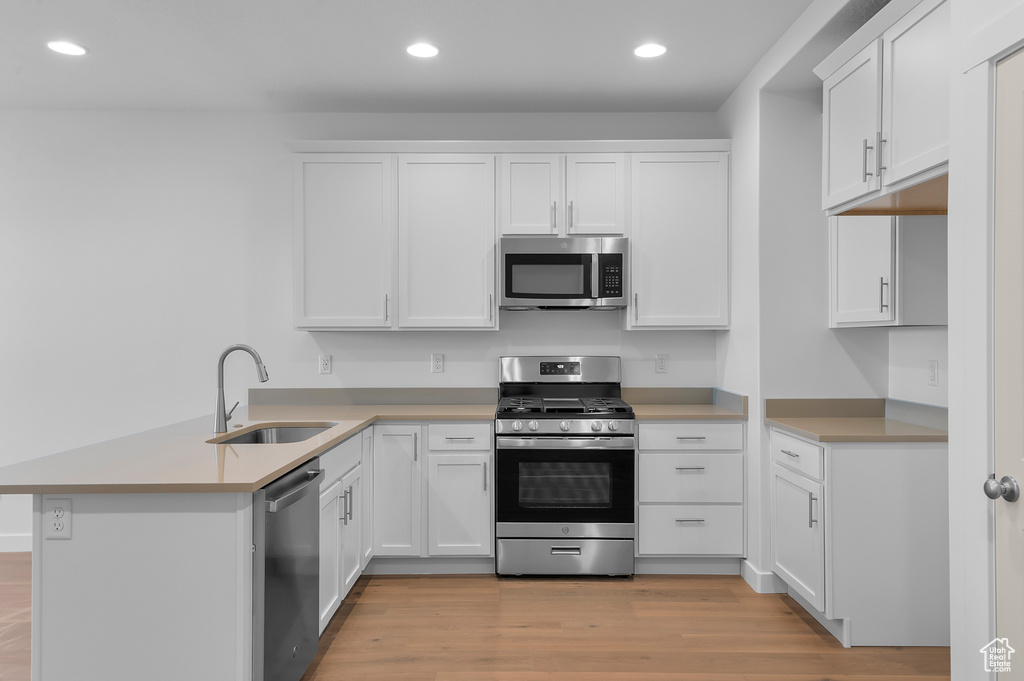Kitchen with a sink, appliances with stainless steel finishes, recessed lighting, and a peninsula