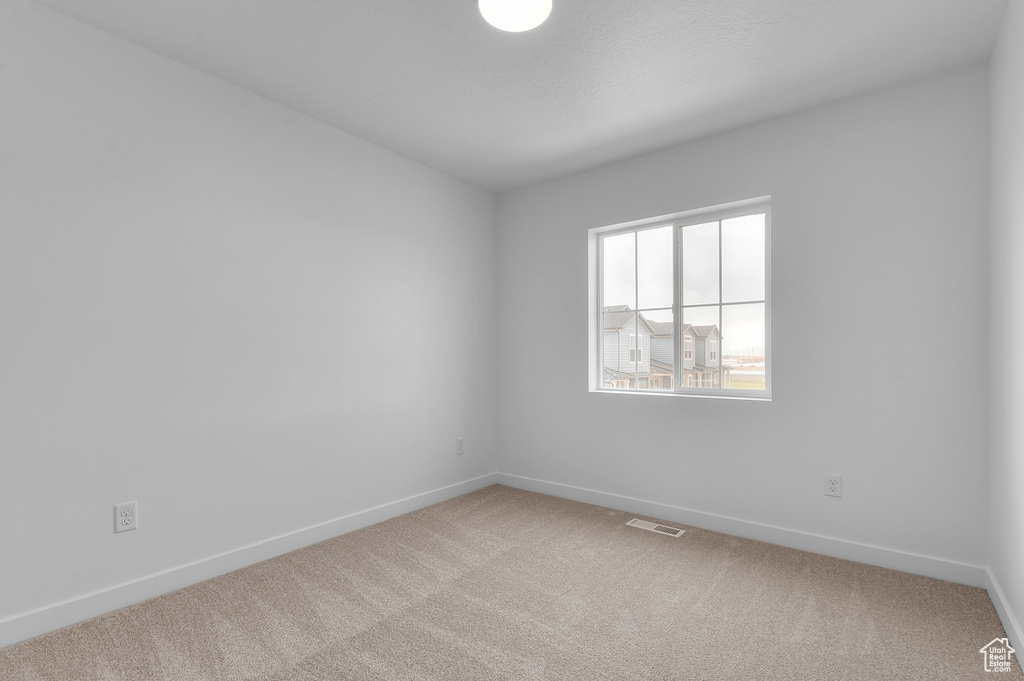 Carpeted empty room featuring visible vents and baseboards