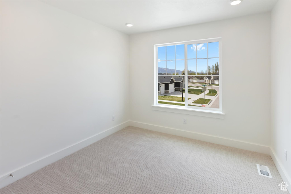 Unfurnished room with baseboards, visible vents, and light carpet